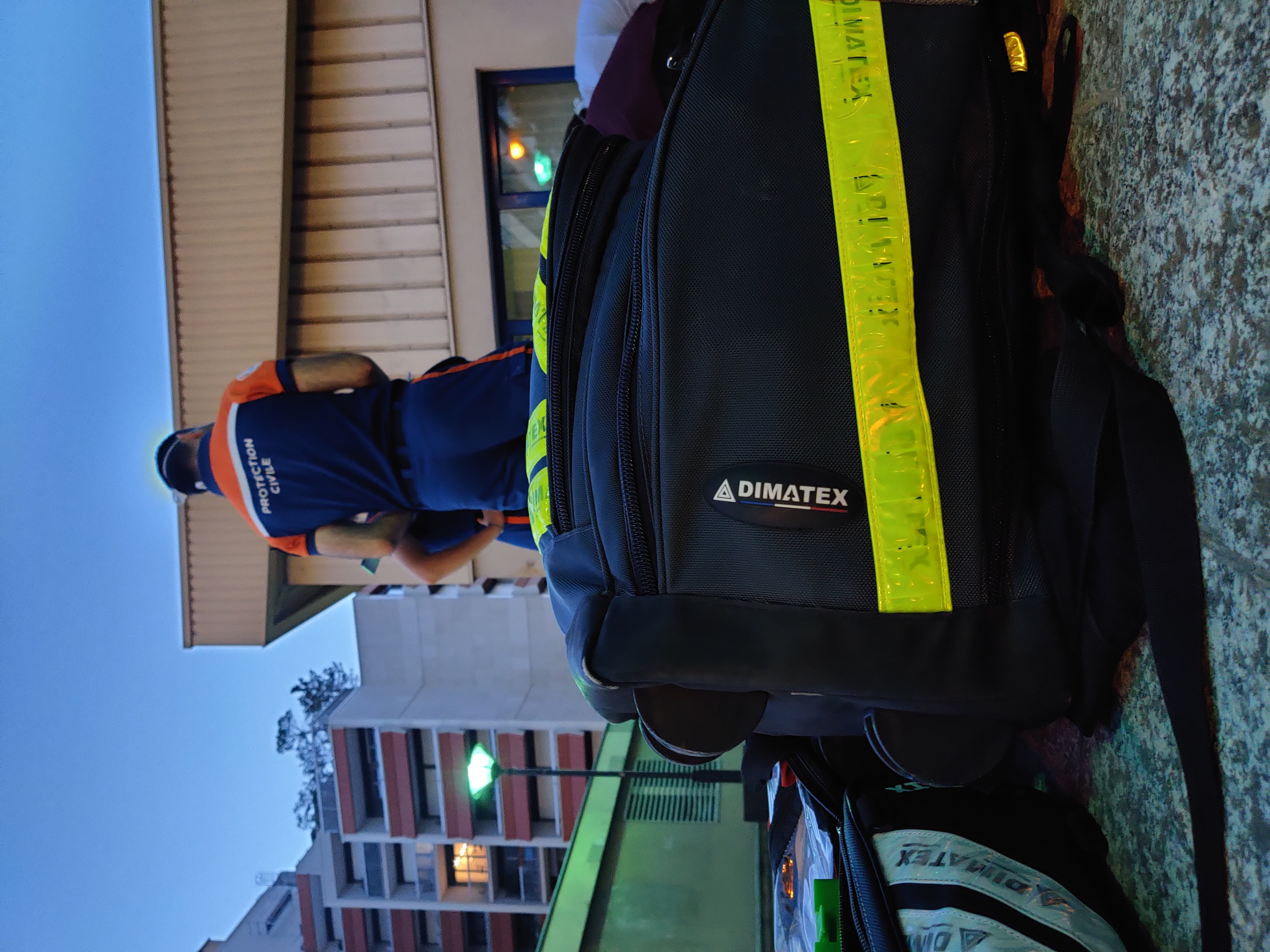 Photo d'une personne en uniforme de la Protection Civile en arrière plan discutant avec un camarade, un sac de soin DIMATEX au premier plan.